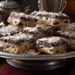 A festive tableau showcasing Chocolate Coconut Almond Bars: layering of textures - a luscious dark chocolate base, followed by a snowy white layer of shredded coconut, and crowned with a roasted almond