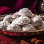 A still life of Mexican wedding cookies artfully arranged on an ornate, antique silver platter.