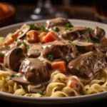 A sumptuous plate of Beef Tenderloin tips Stroganoff rest on as bed of egg noodles in a creamy sauce complemented by sautéed mushrooms